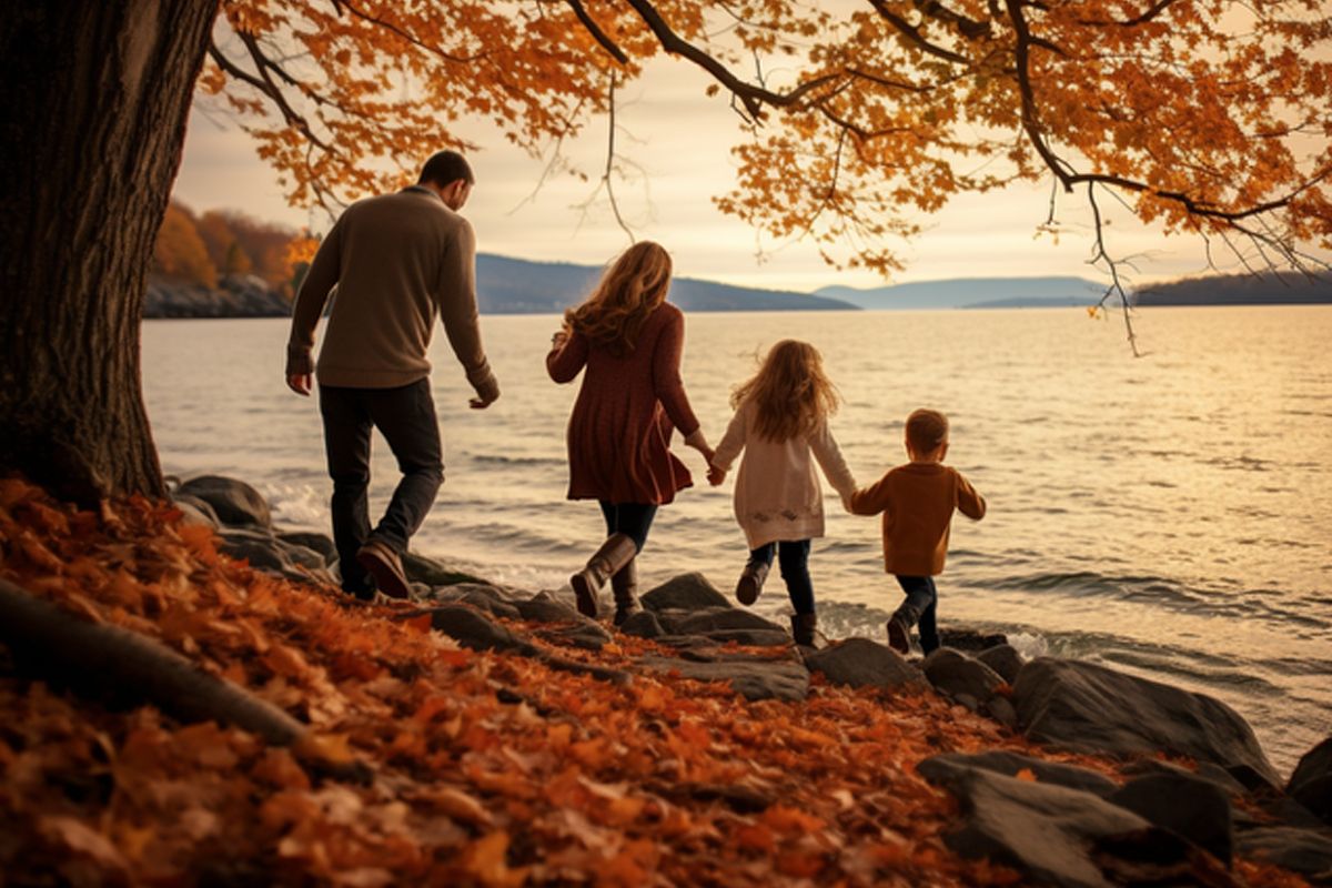 Eine Familie geht am Wasser entlang, umgeben von bunten Herbstblättern