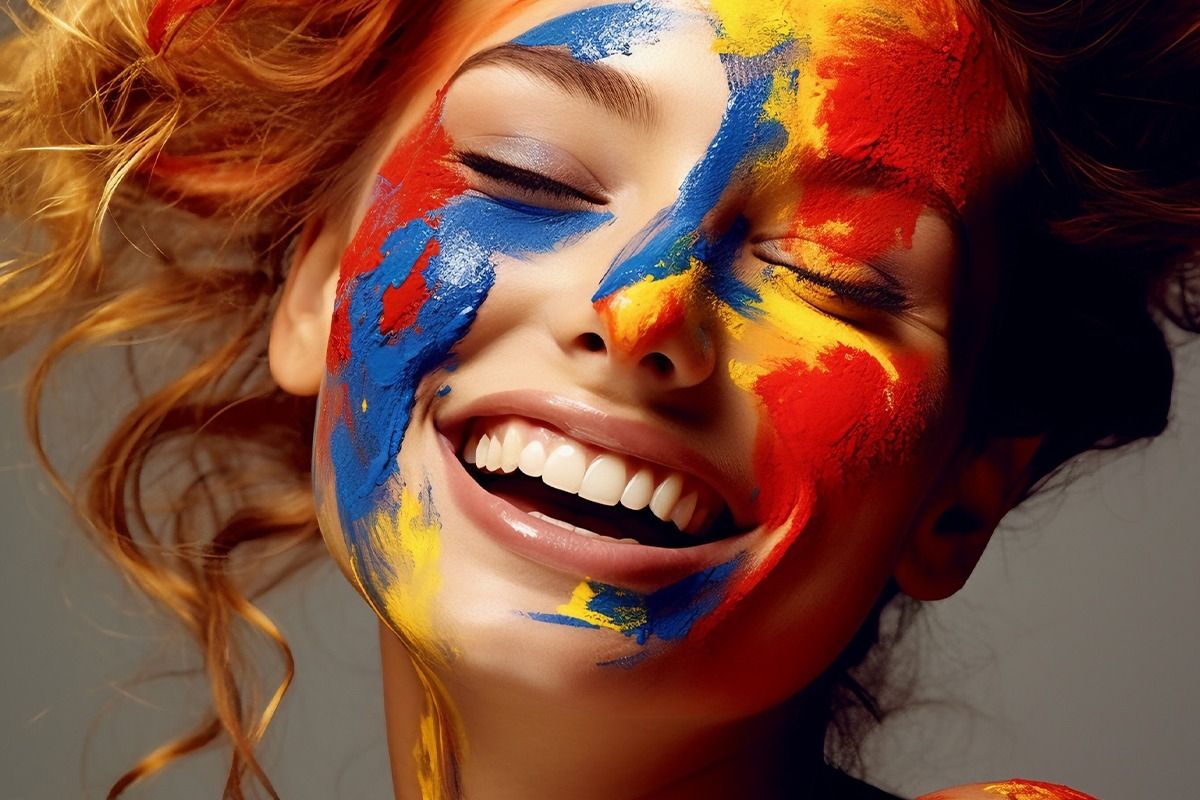 Eine Frau die lächelt mit gelb, roter und blauer Farbe im Gesicht.