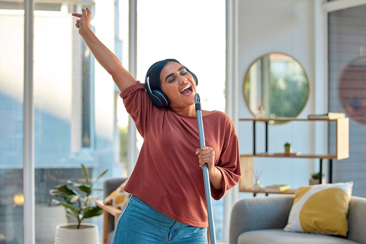 Frau hat Kopfhörer drauf und singt während des Putzens.