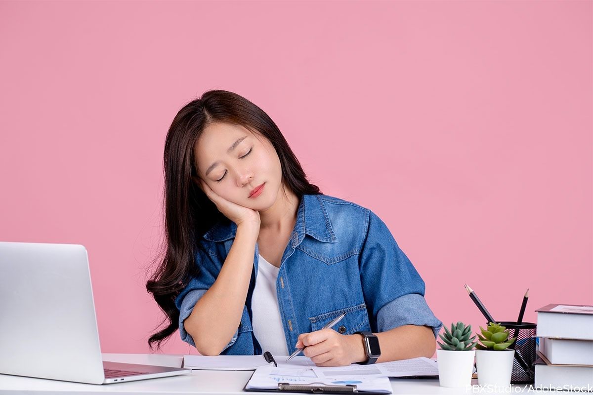 Frau schläft am Arbeitsplatz ein.