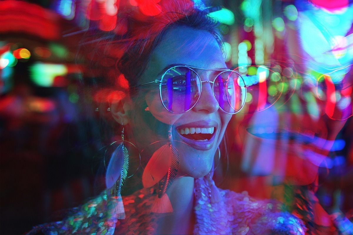 Frau im Partyoutfit, die umgeben ist von Neonlichtern.