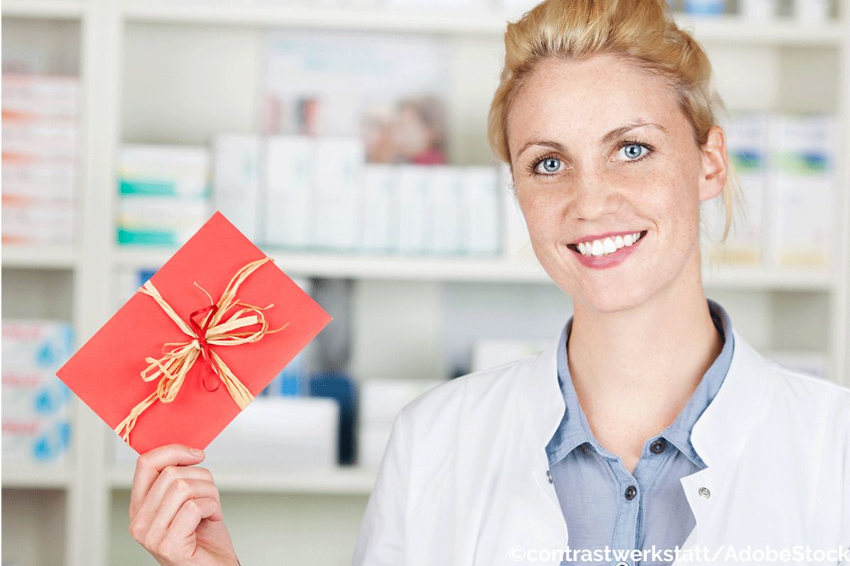 Apothekerin hält eine rote Geschenkkarte in der Apotheke.