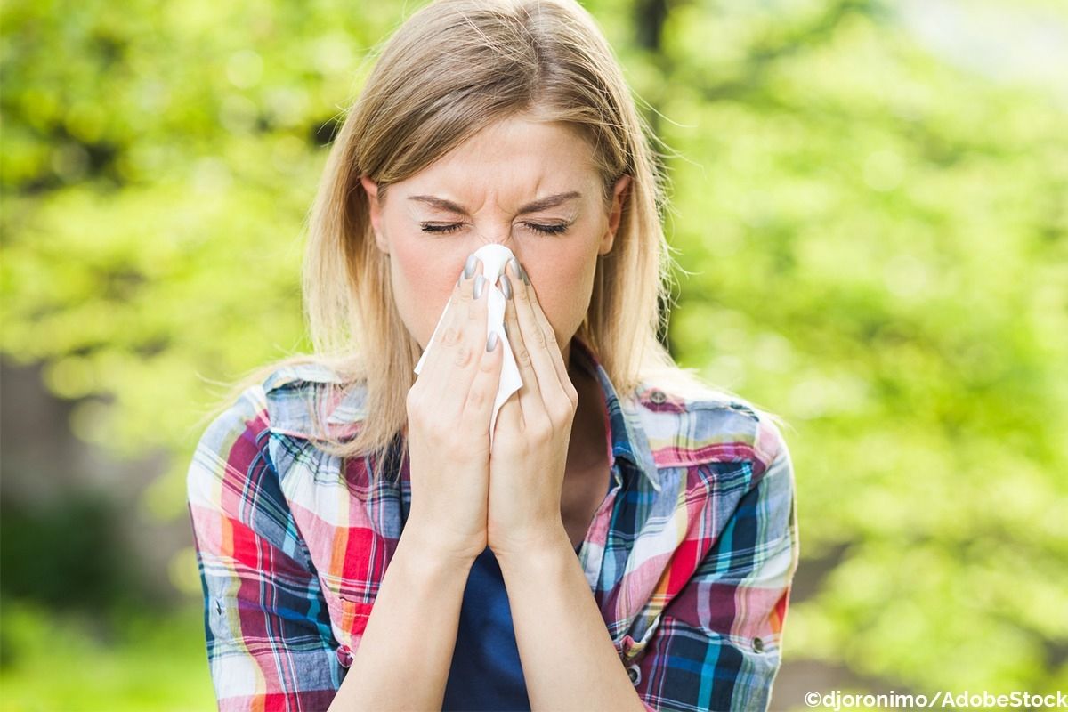 Eine Frau niest in ein Taschentuch.
