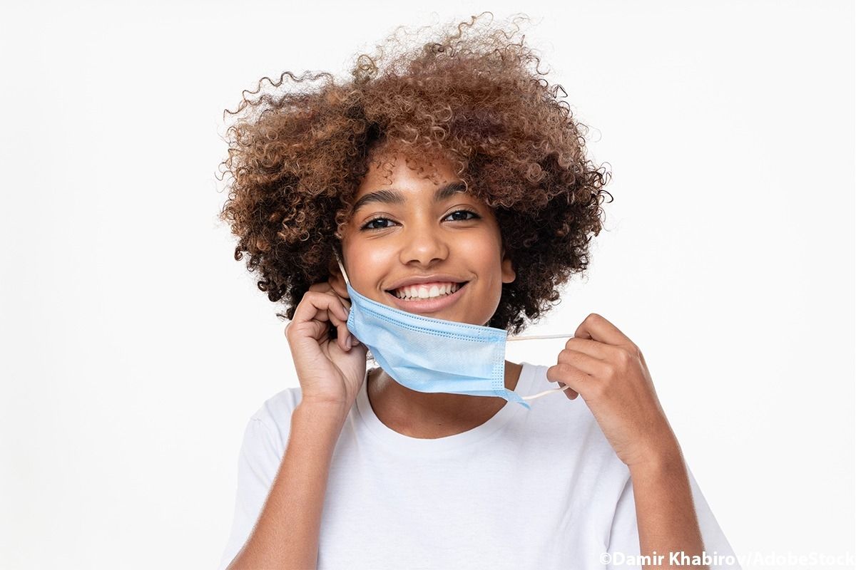 Frau setzt sich eine Maske auf.