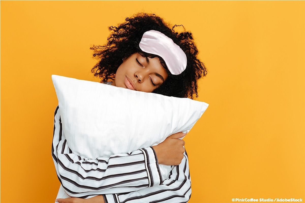 Frau im Schlafanzug umarmt ein Kissen.