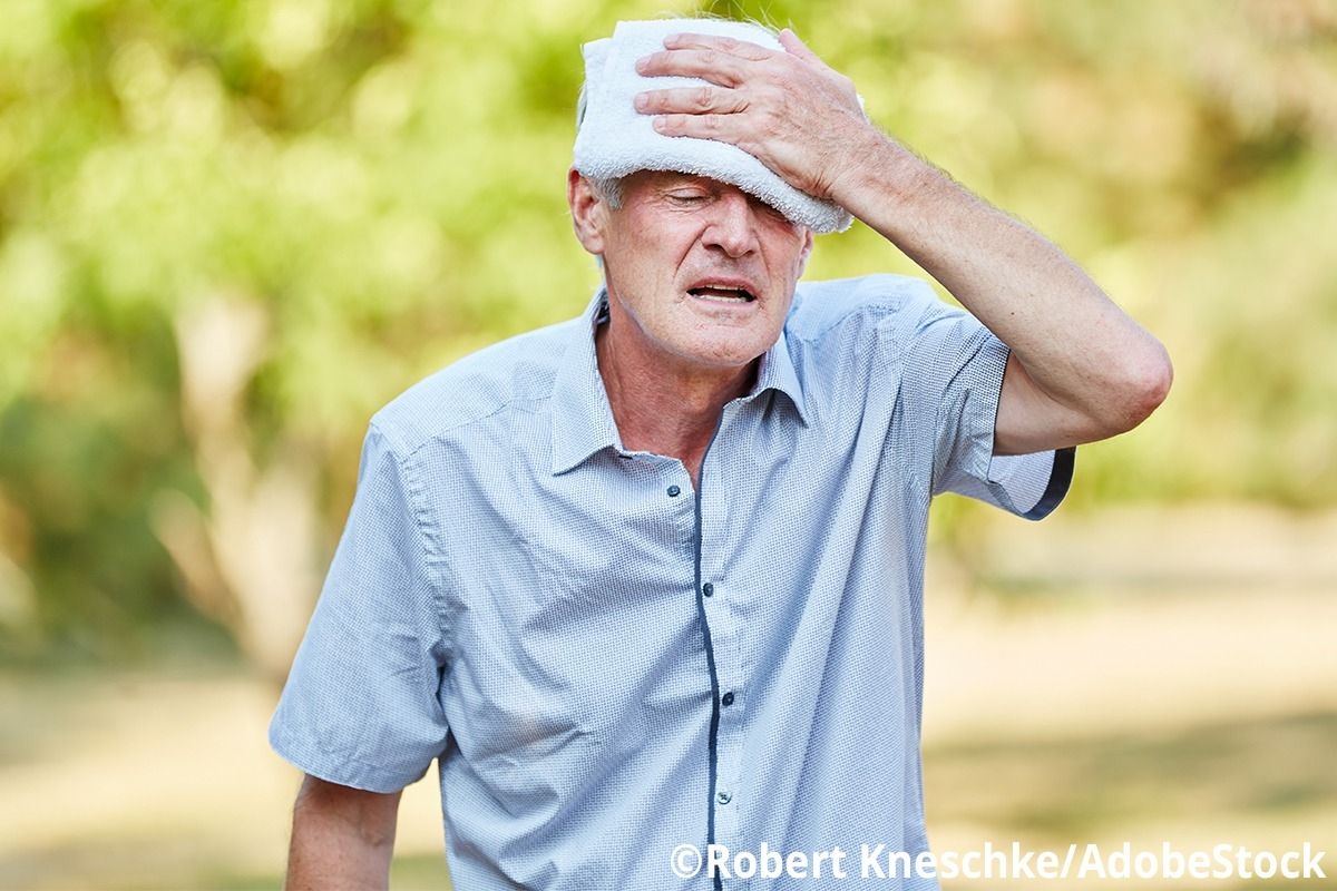 Mann hat ein Tuch an die Stirn gehalten und schwitzt.