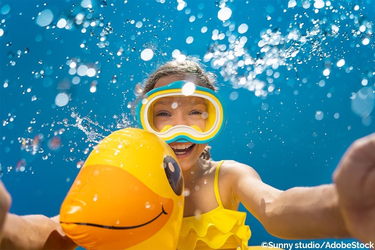 Mädchen taucht unter Wasser mit einem Gummiring zum Schwimmen.