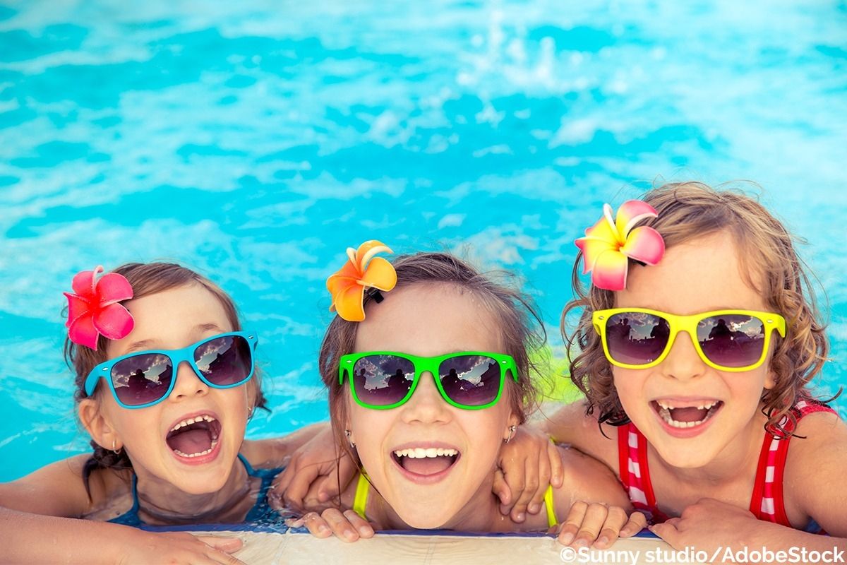 Drei Mädchen plantschen im Pool mit Sonnenbrille.