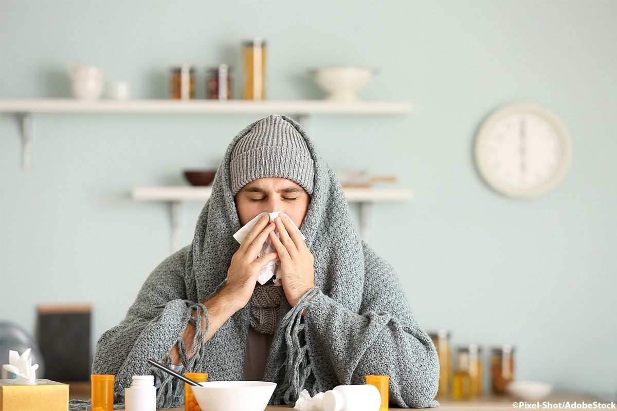 Mann sitzt erkältet vor Medikamenten.