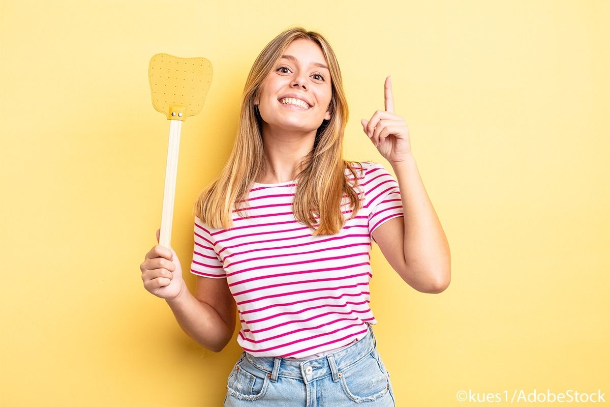 Frau mit gestreiftem Oberteil hält eine gelbe Fliegenklatsche hoch.