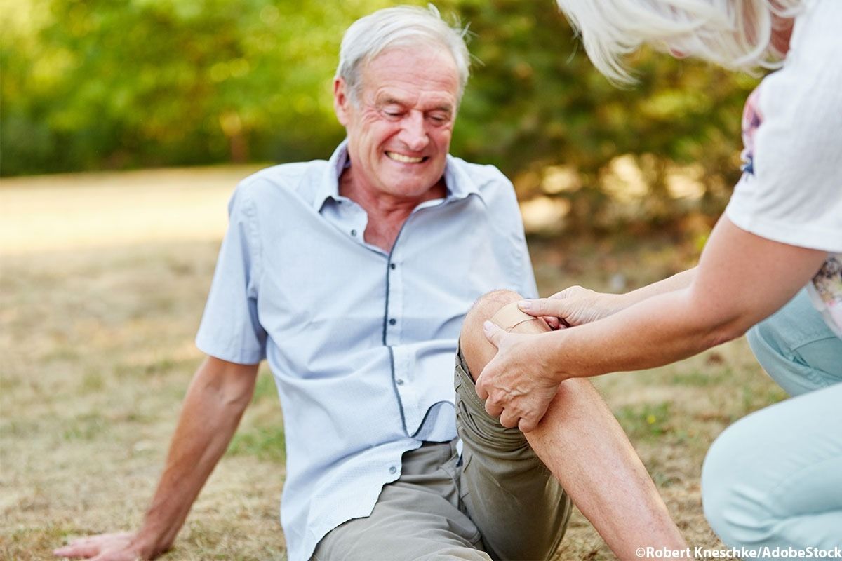 Eine Frau klebt ein Pflaster auf das verletzte Knie eines Mannes.