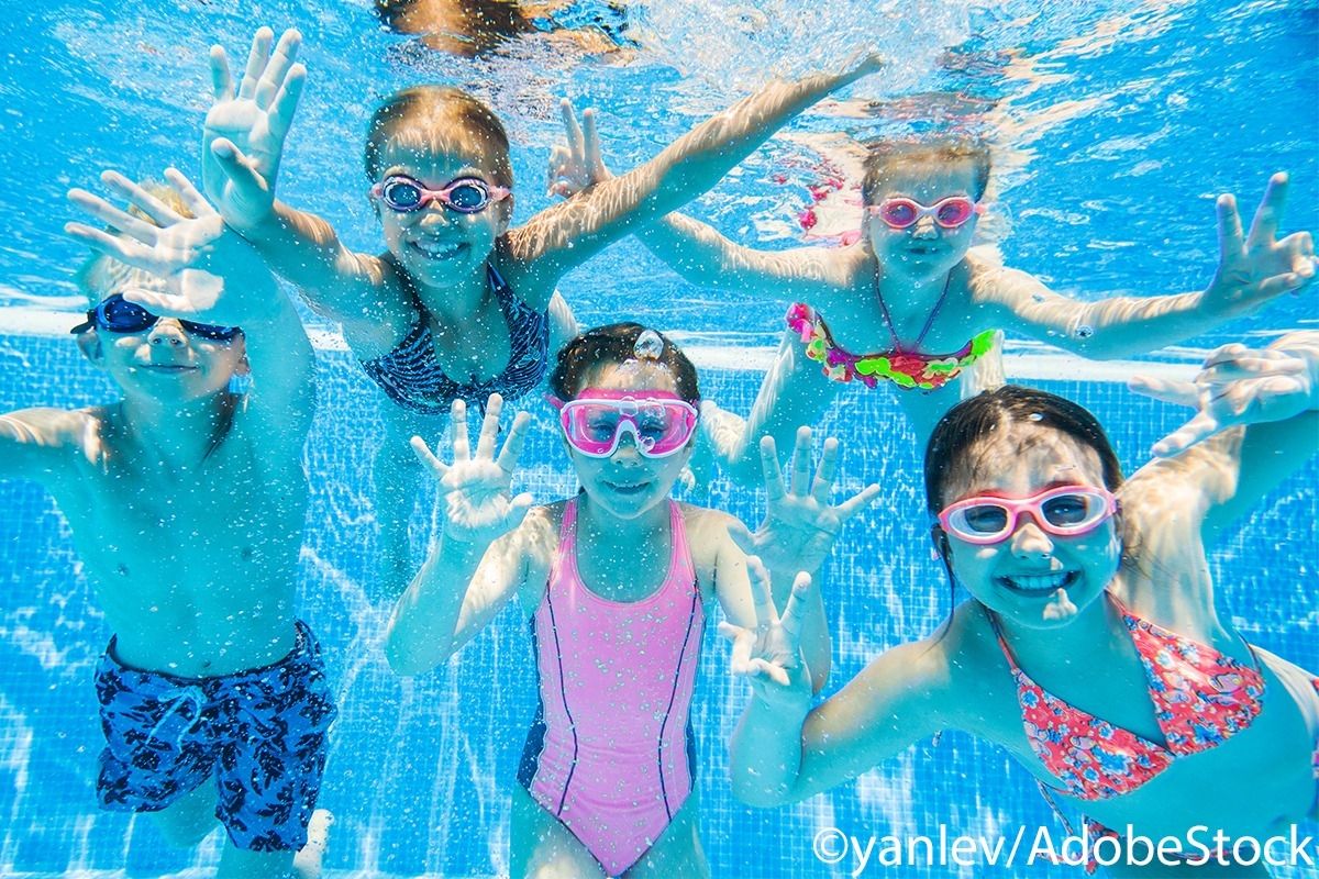 Fünf Kinder tauchen Unterwasser und winken in die Kamera