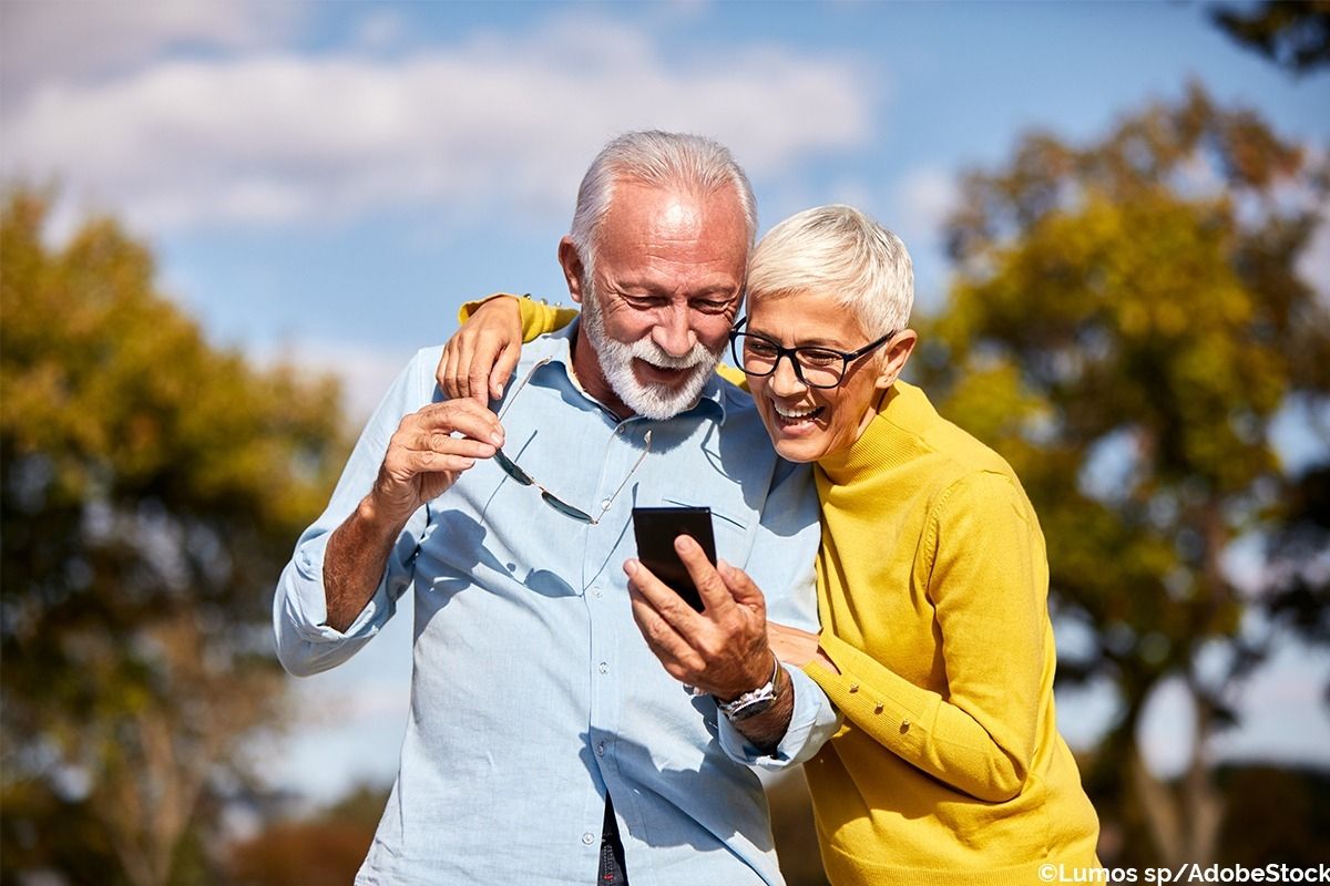 Älteres Pärchen schaut gemeinsam in ein Smartphone.