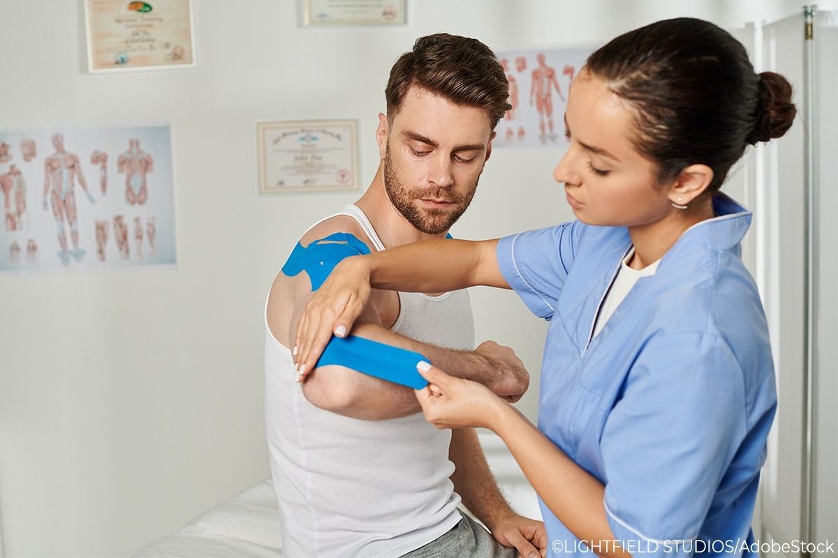 Eine Krankenschwester tapt den rechten Arm eines Patienten.