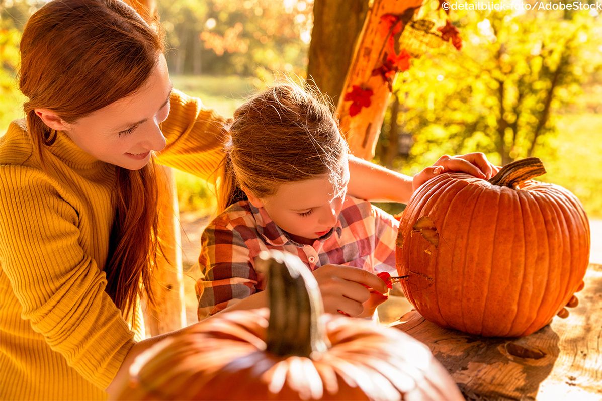 Eine Mutter und Tochter schnitzen gemeinsam einen Kürbis im Herbst.