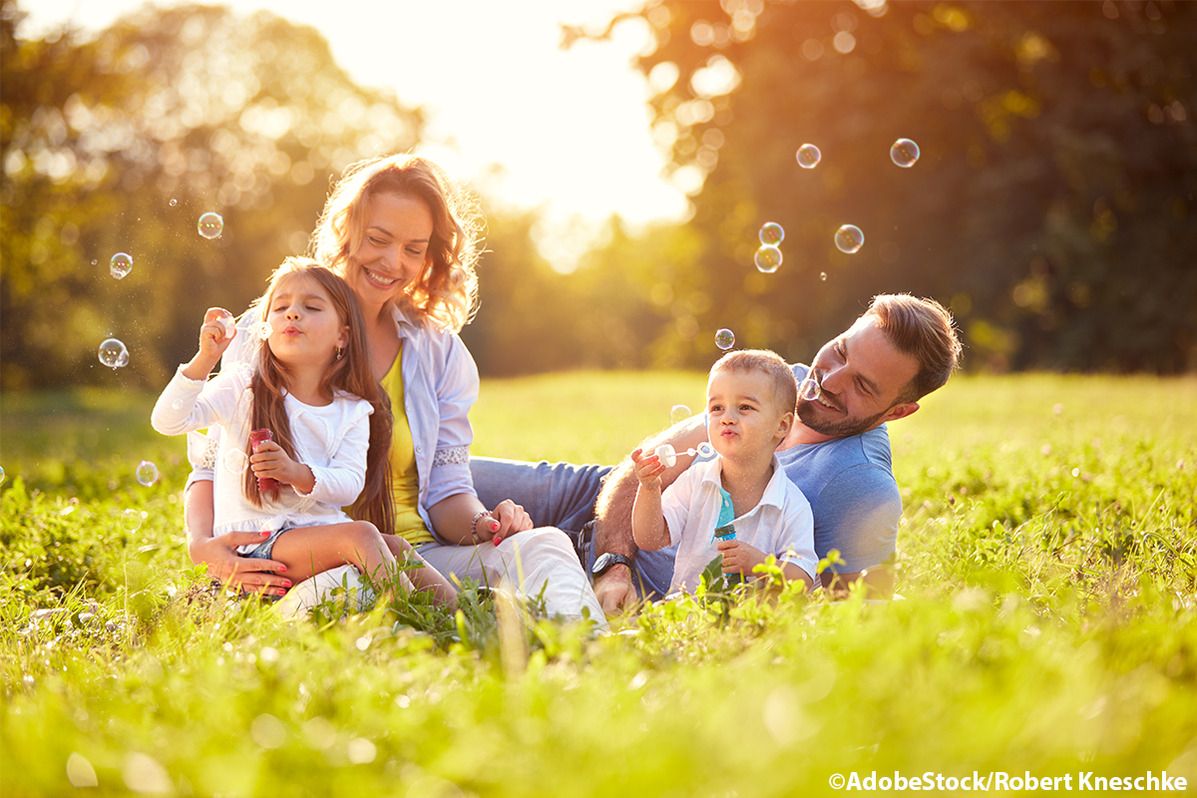 Eine glückliche Familie spielt im Feld und bläst Seifenblasen.