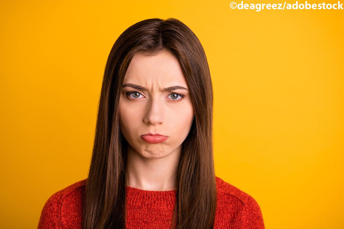 Unglückliches Mädchen mit traurigem Gesichtsausdruck vor gelbem Hintergrund