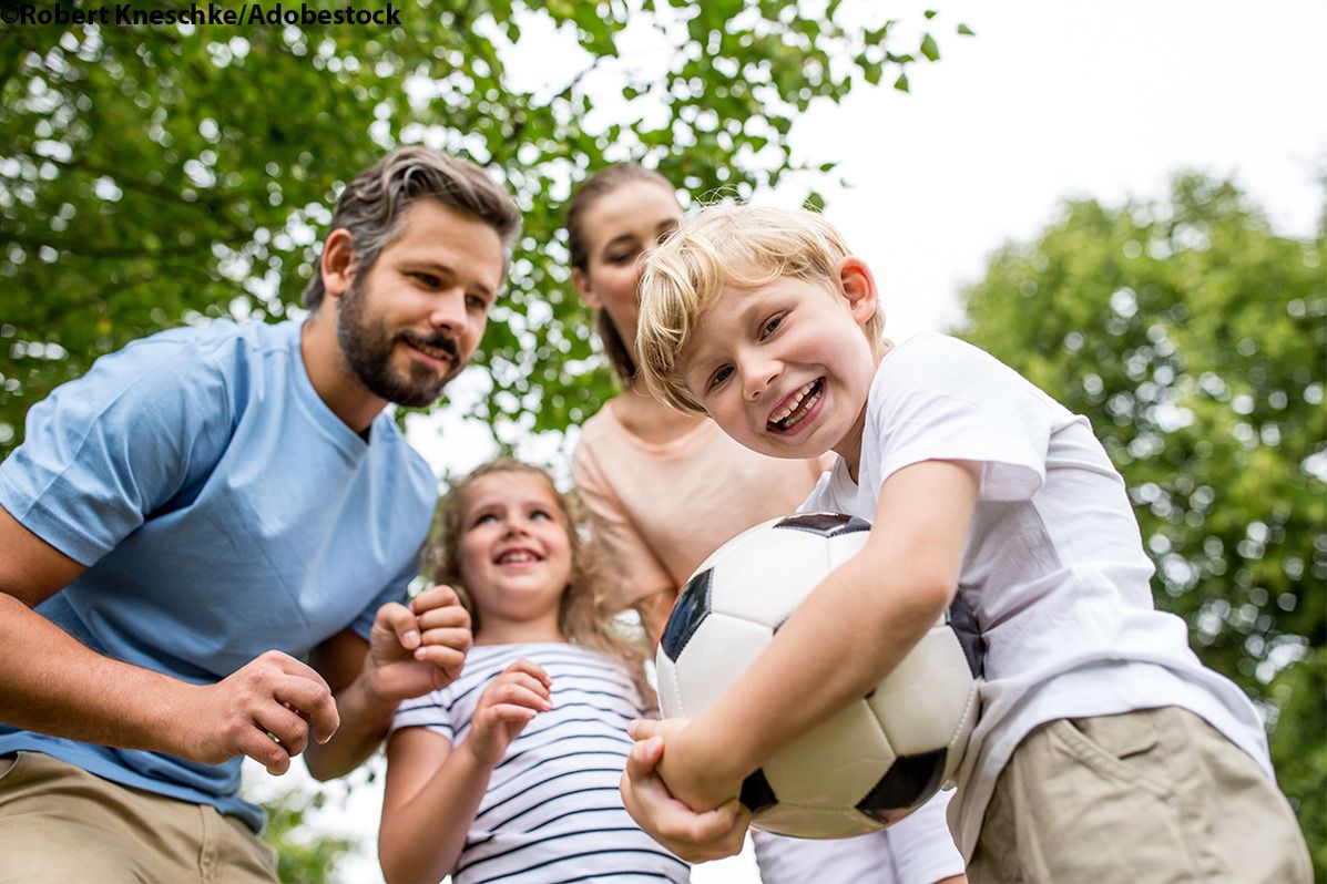 Eine Familie spielt im Freien mit einem Fußball