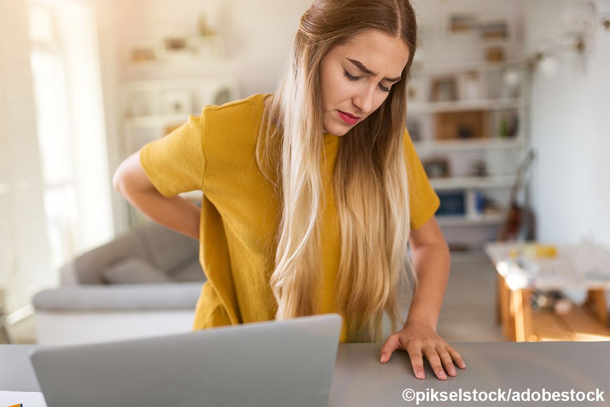 Eine Frau mit Rückenschmerzen im Home Office
